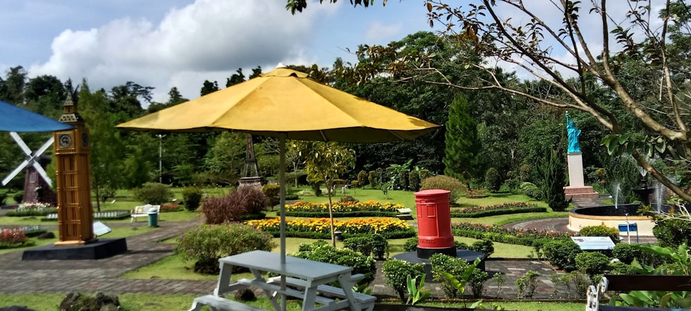 a park with a bench and a yellow umbrella