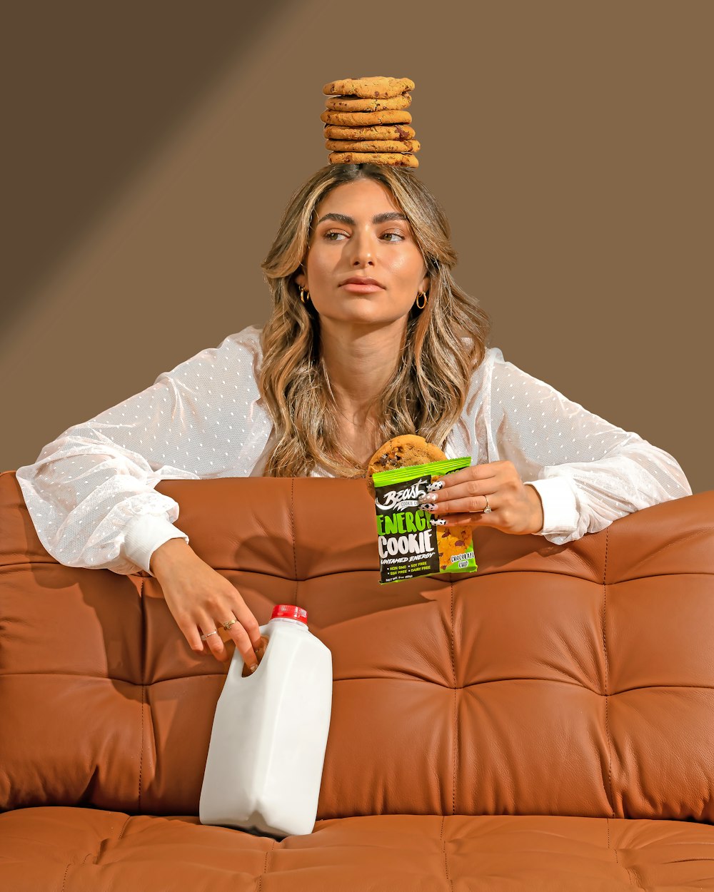 a woman sitting on a couch with a stack of cookies on her head