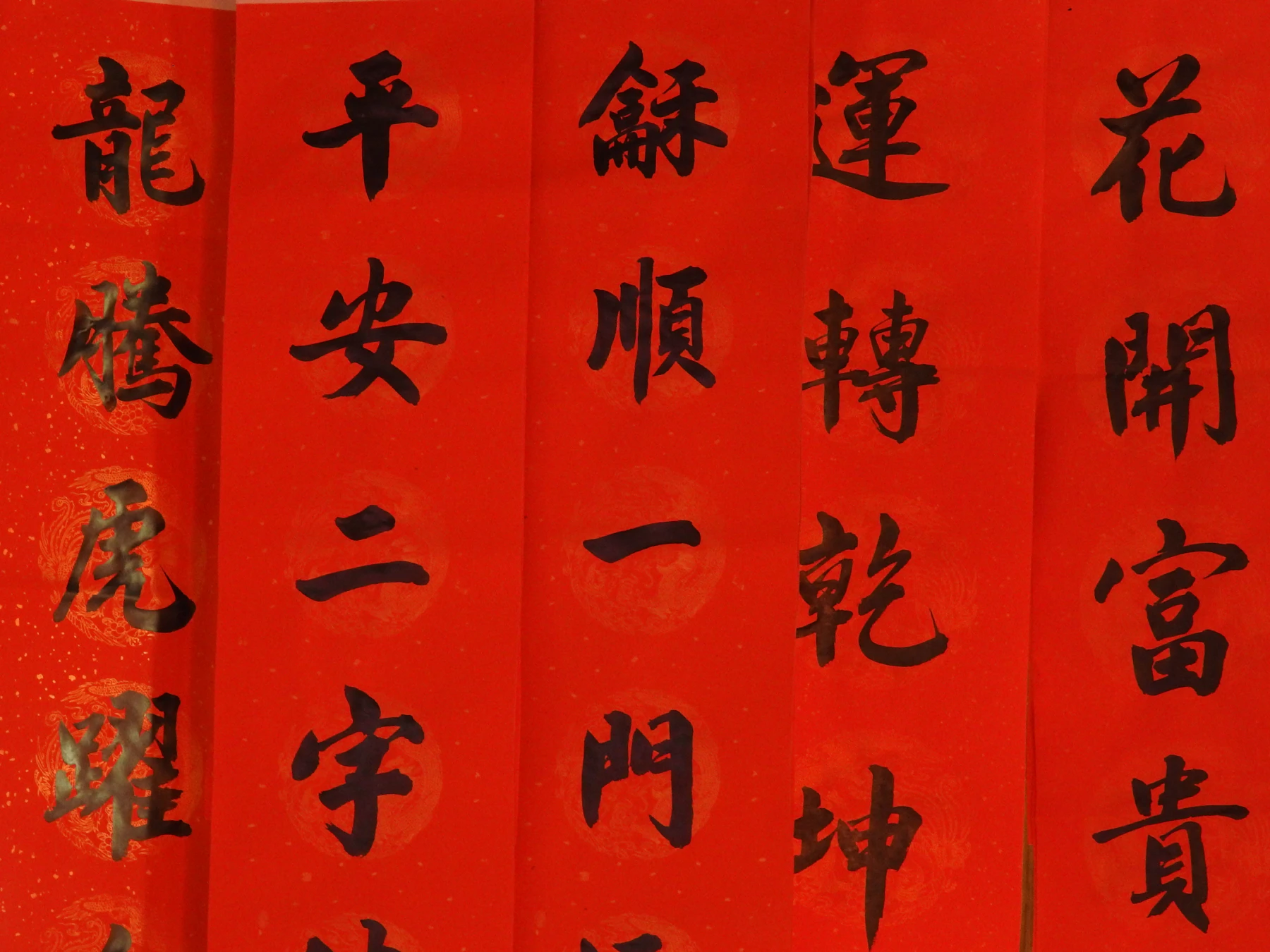 Strips of bright red paper hung side by side, each brushed top to bottom with large black Chinese characters