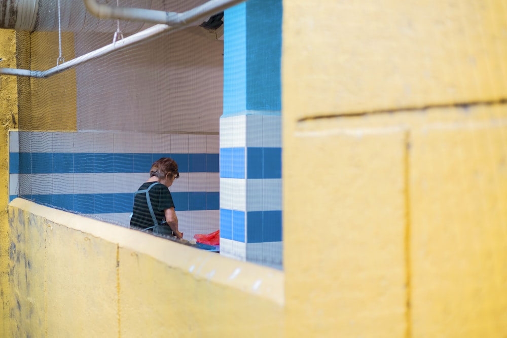 a woman standing in a bathroom next to a blue and yellow wall