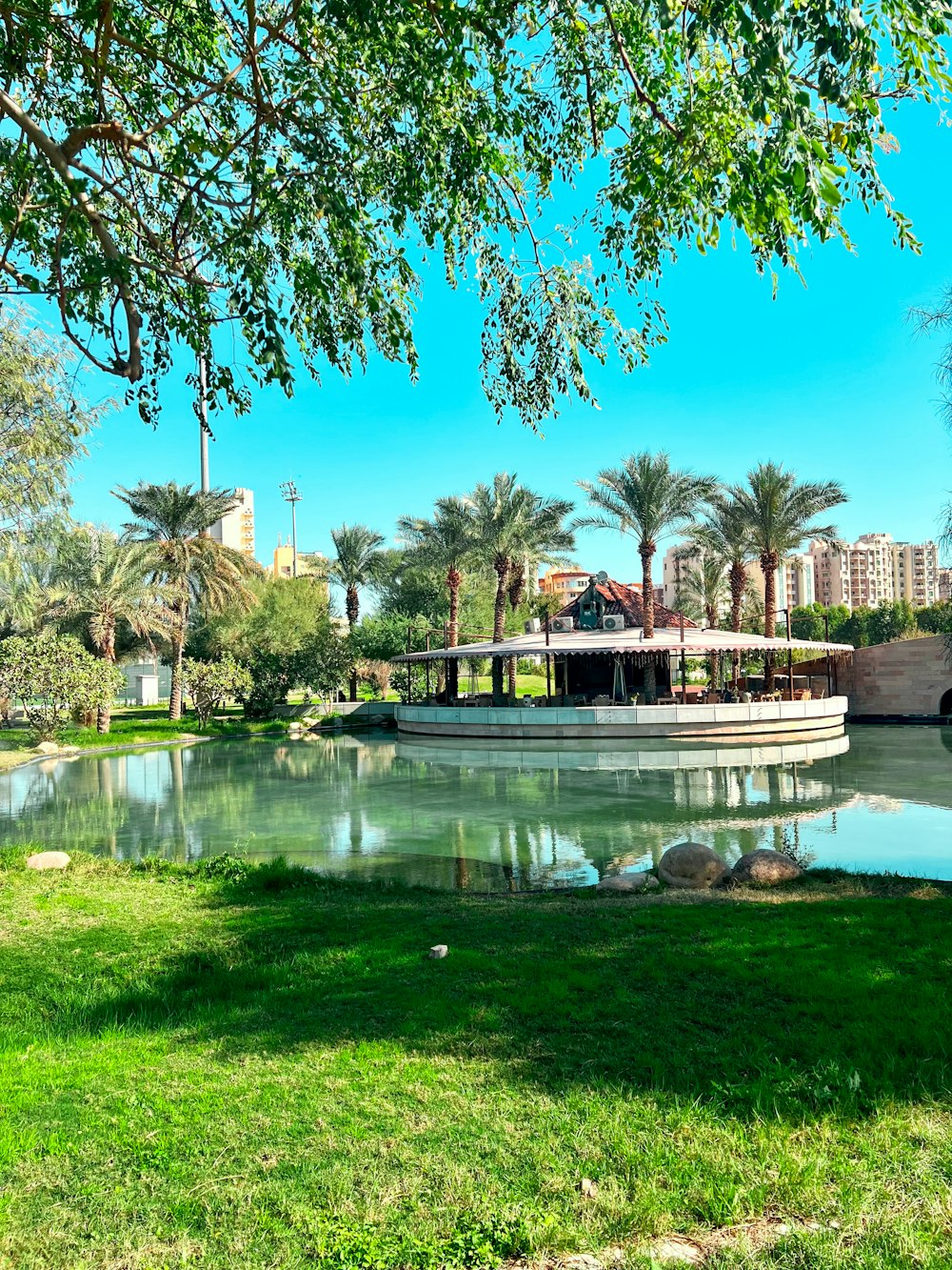 a boat floating on top of a lake next to a lush green park