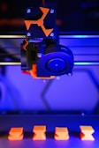 A close up of a 3d printer with a blue light