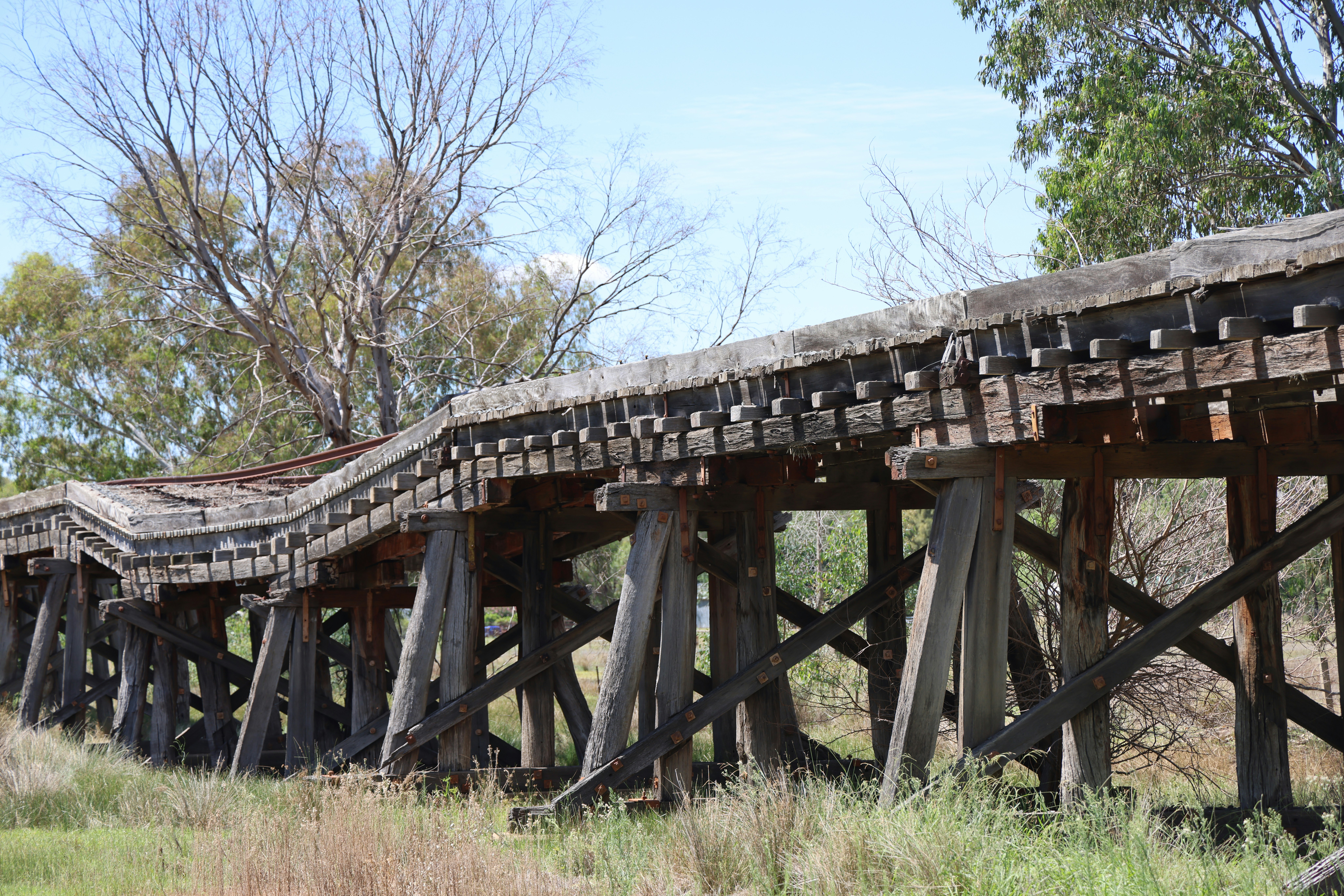 an old wooden bridge in the middle of a field