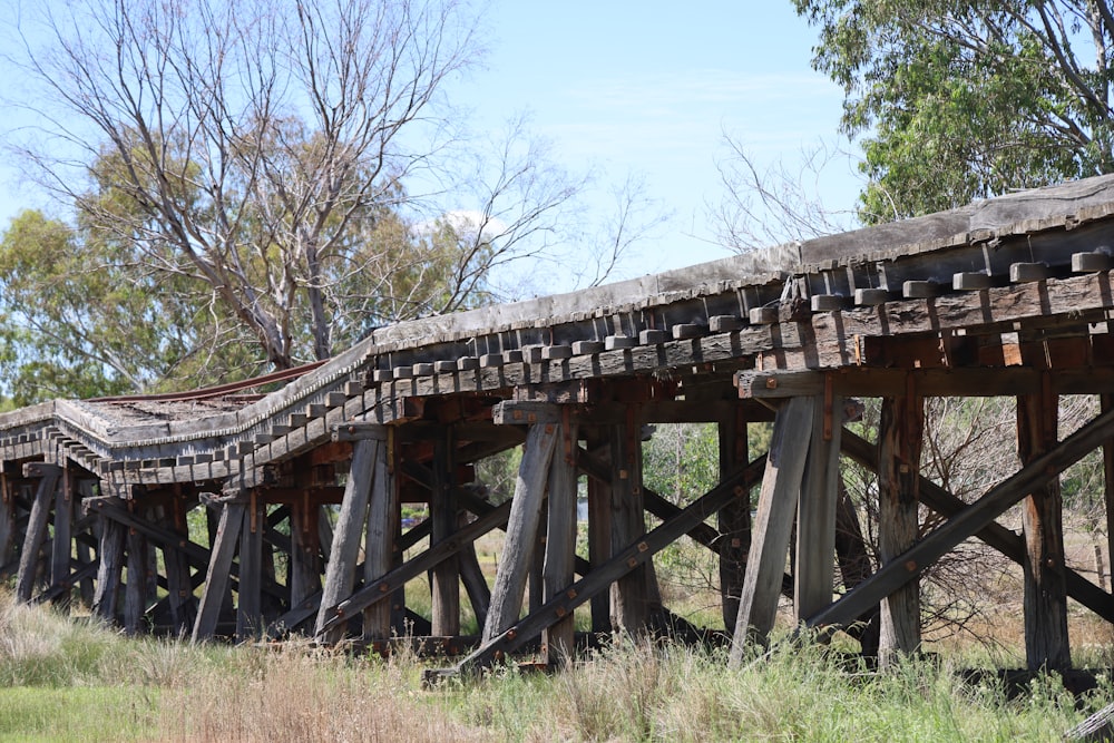 an old wooden bridge in the middle of a field