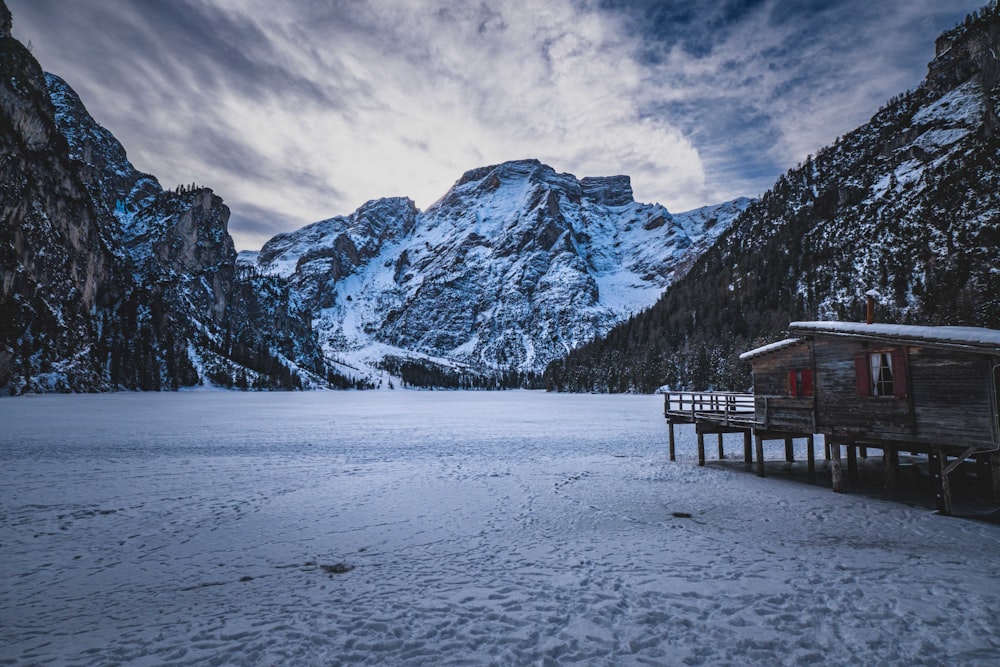 a snowy landscape with a cabin in the foreground and mountains in the background