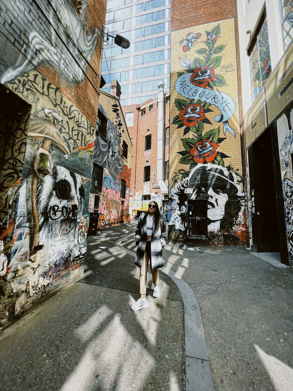 a woman walking down a street with graffiti on the walls