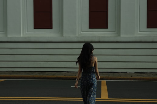 a woman walking across a street in front of a building