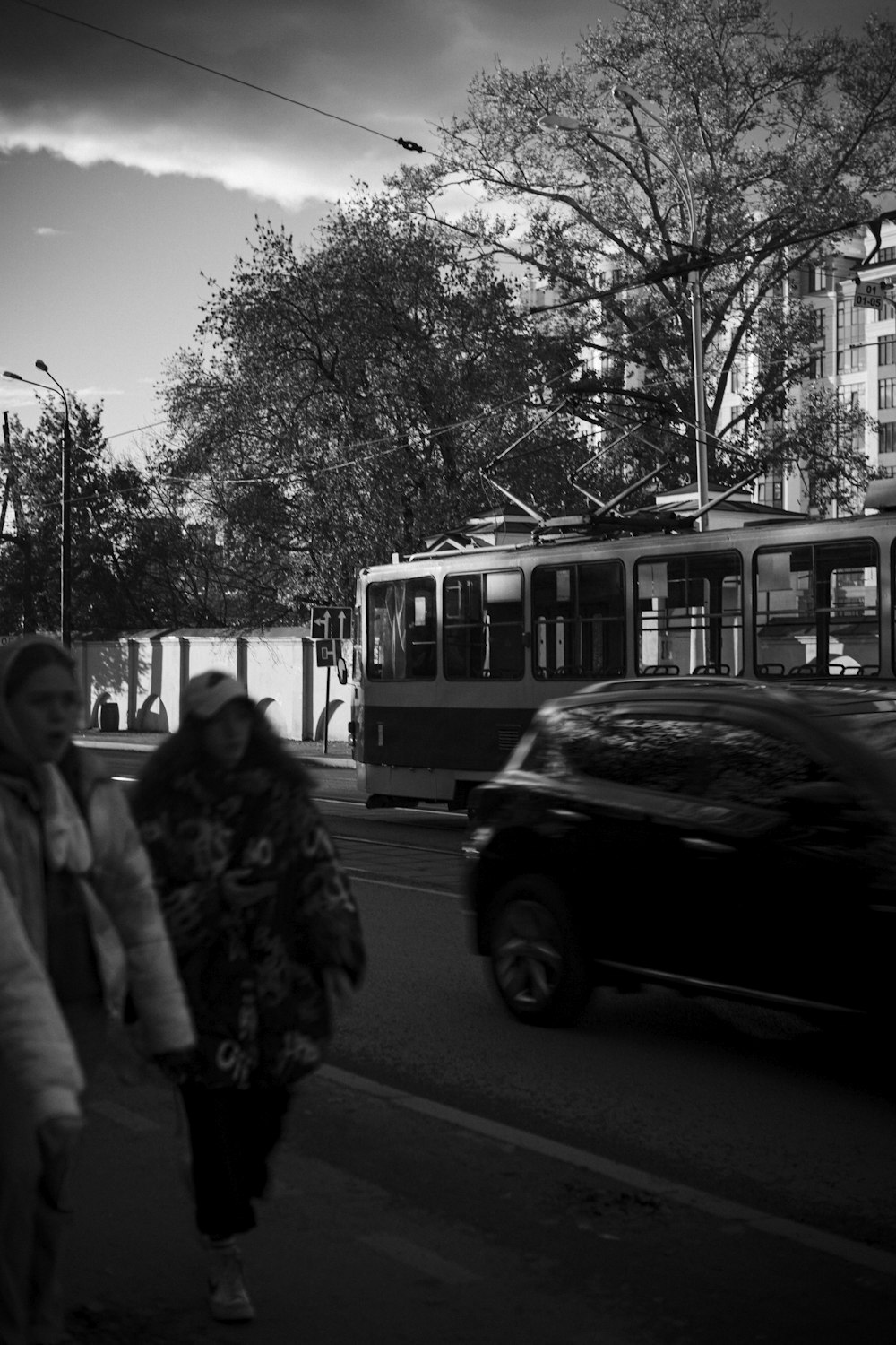 a black and white photo of two people walking on the sidewalk