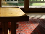 a wooden table sitting on top of a red rug