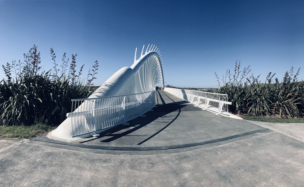 a curved walkway with a white bridge in the background