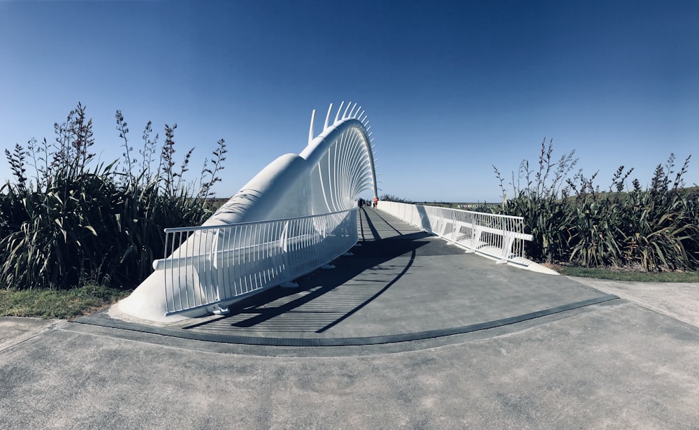 una pasarela curva con un puente blanco al fondo