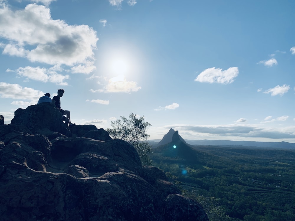 un paio di persone sedute in cima a una montagna