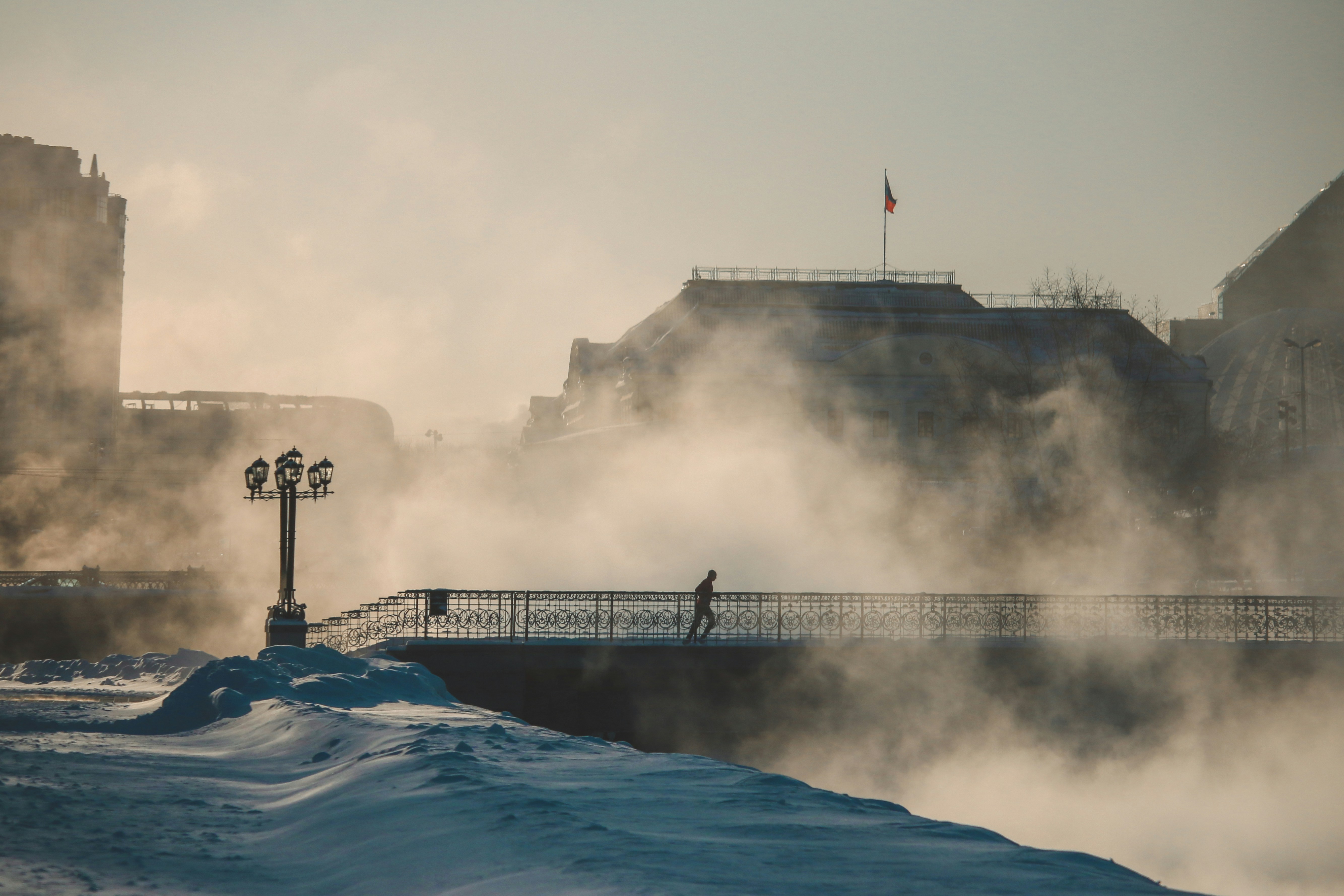 a person walking across a bridge over a snow covered river
