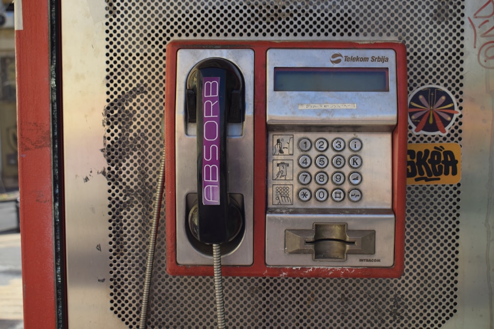 an old style pay phone with a purple sticker on it