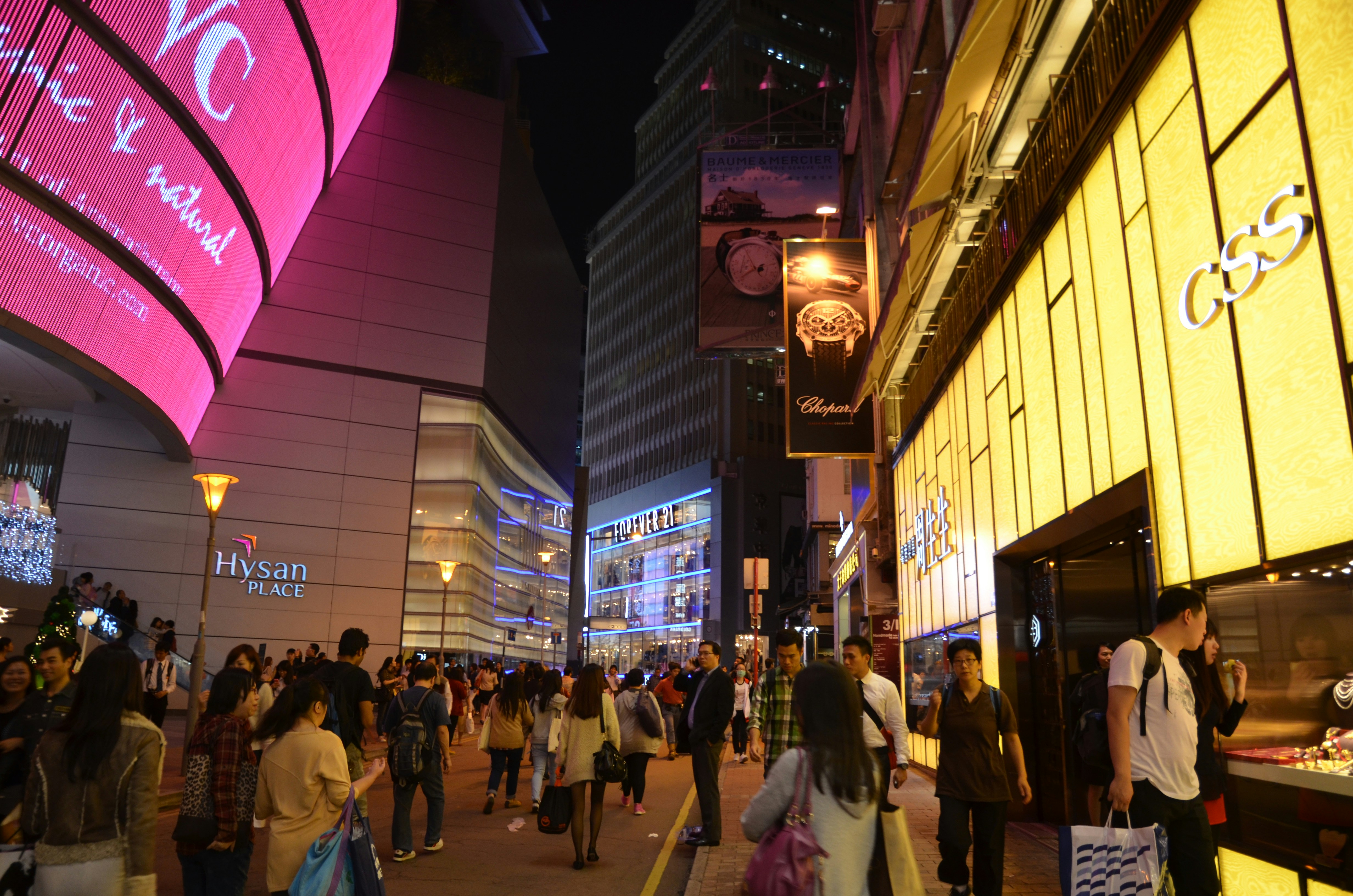 a crowd of people walking down a street next to tall buildings