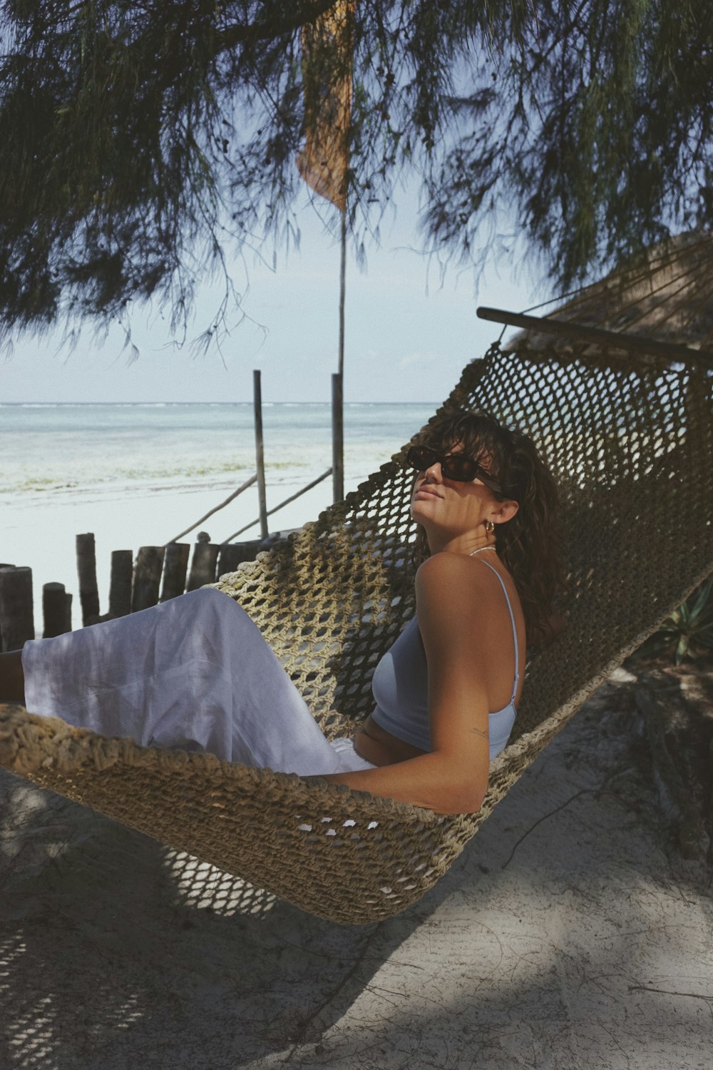 a woman laying in a hammock on the beach