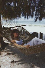 a woman laying in a hammock on the beach