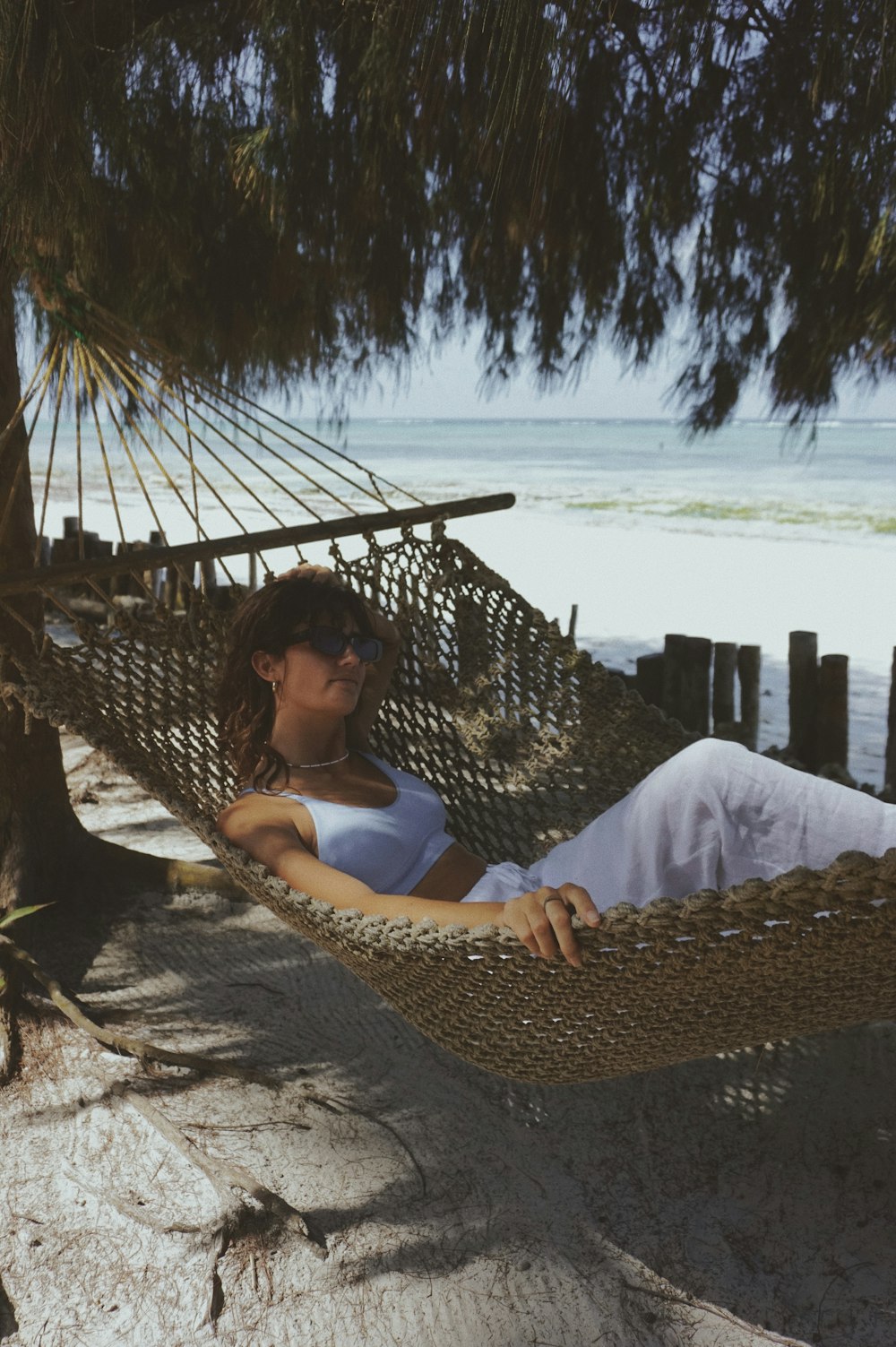 a woman laying in a hammock on the beach