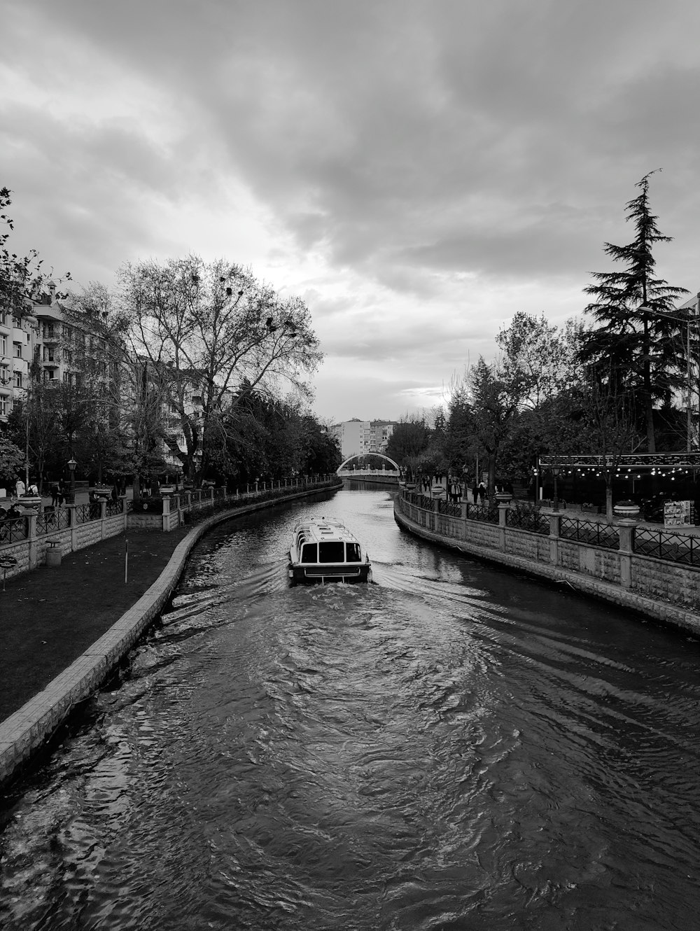 a black and white photo of a boat traveling down a river