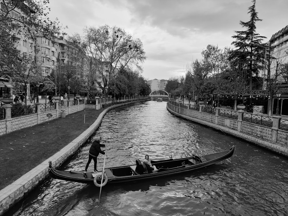 a man standing on the side of a boat on a river