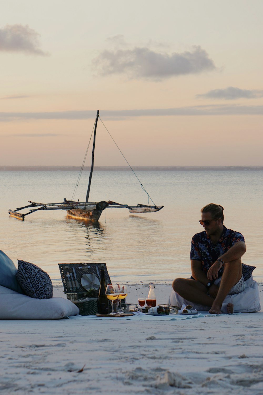 a man sitting on a beach next to a boat