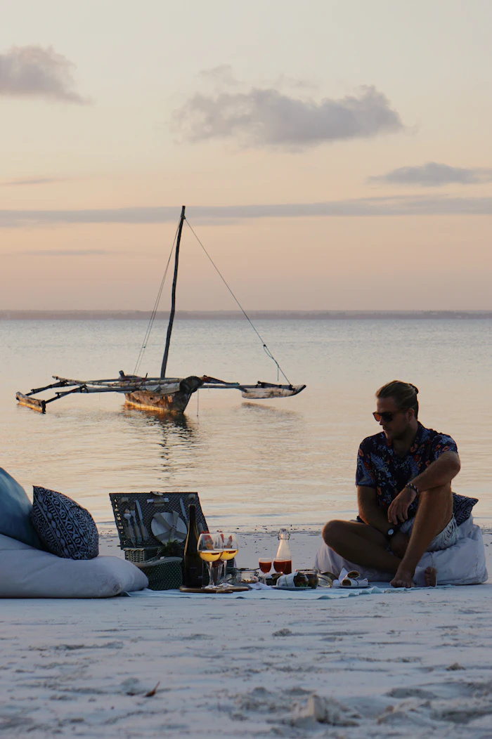 A man relaxing on a Zanzibar beach next to a traditional boat