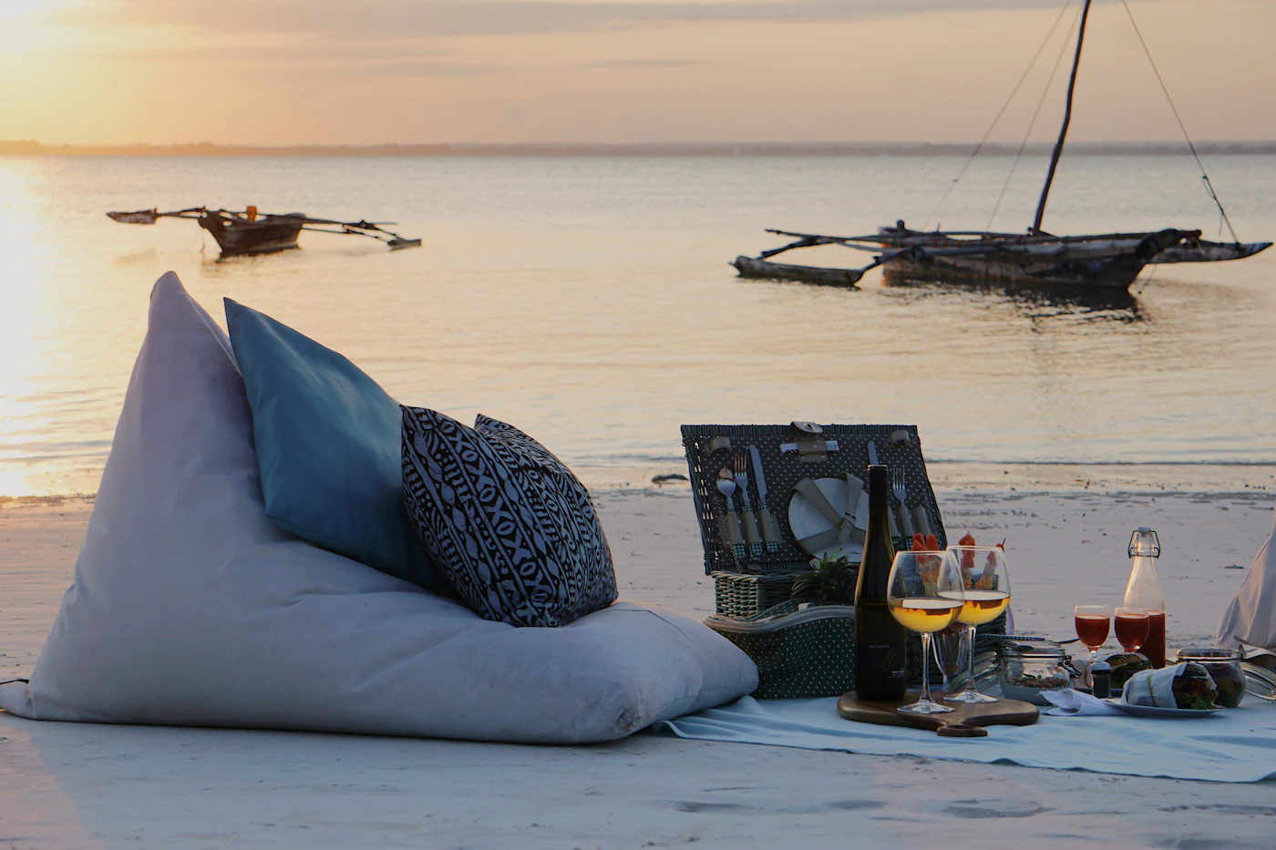 Piquenique de luxo montado ao pôr do sol com almofadas e mesa baixa