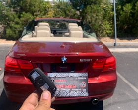 a person holding a car keys in front of a red car