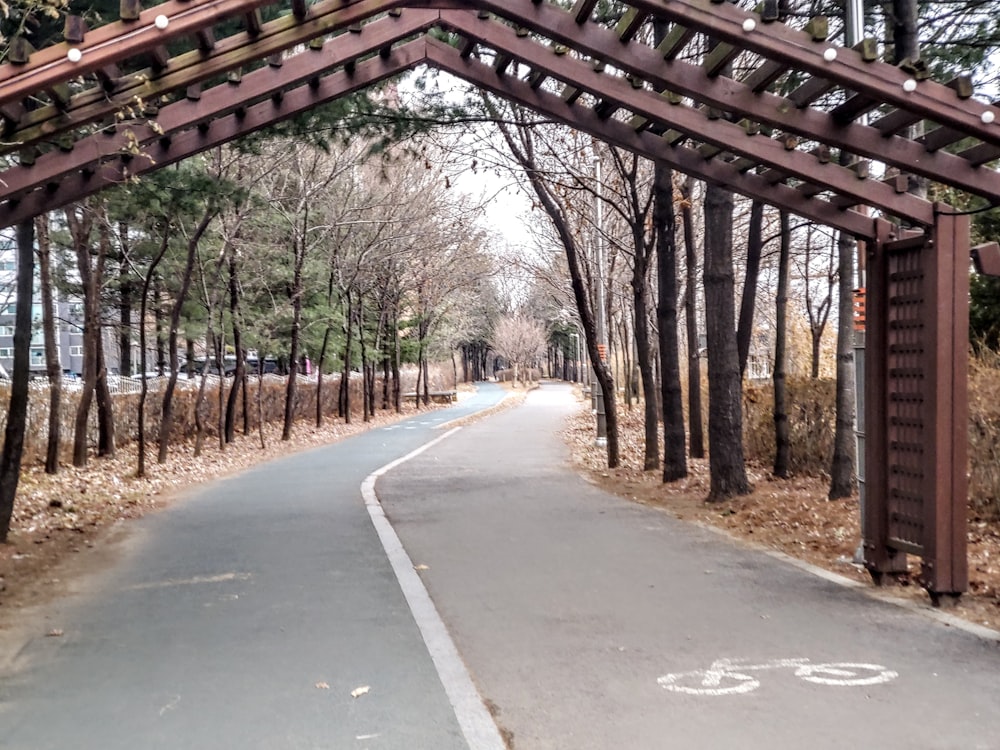 a bike path under a wooden structure in a park