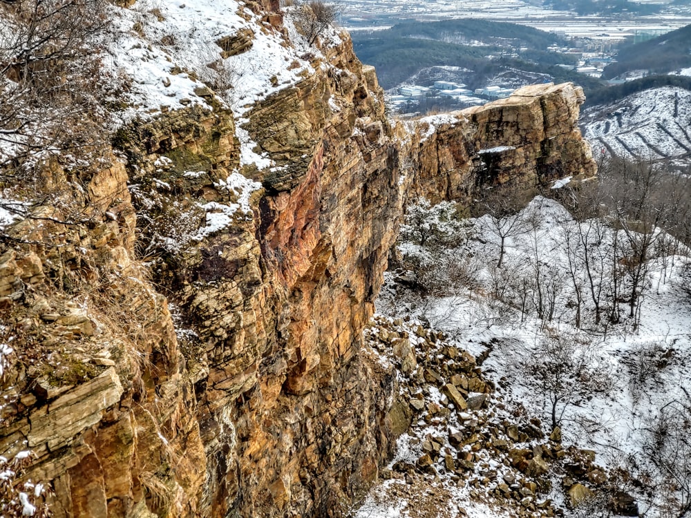 a rocky cliff with snow on the ground