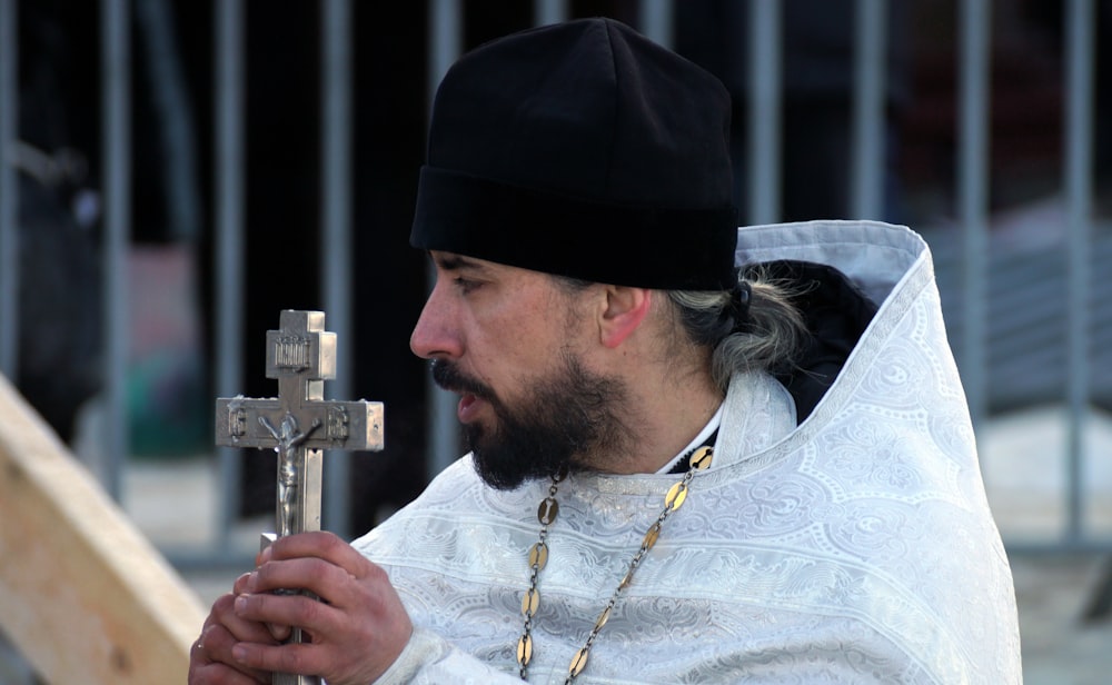 a man in a white robe holding a cross