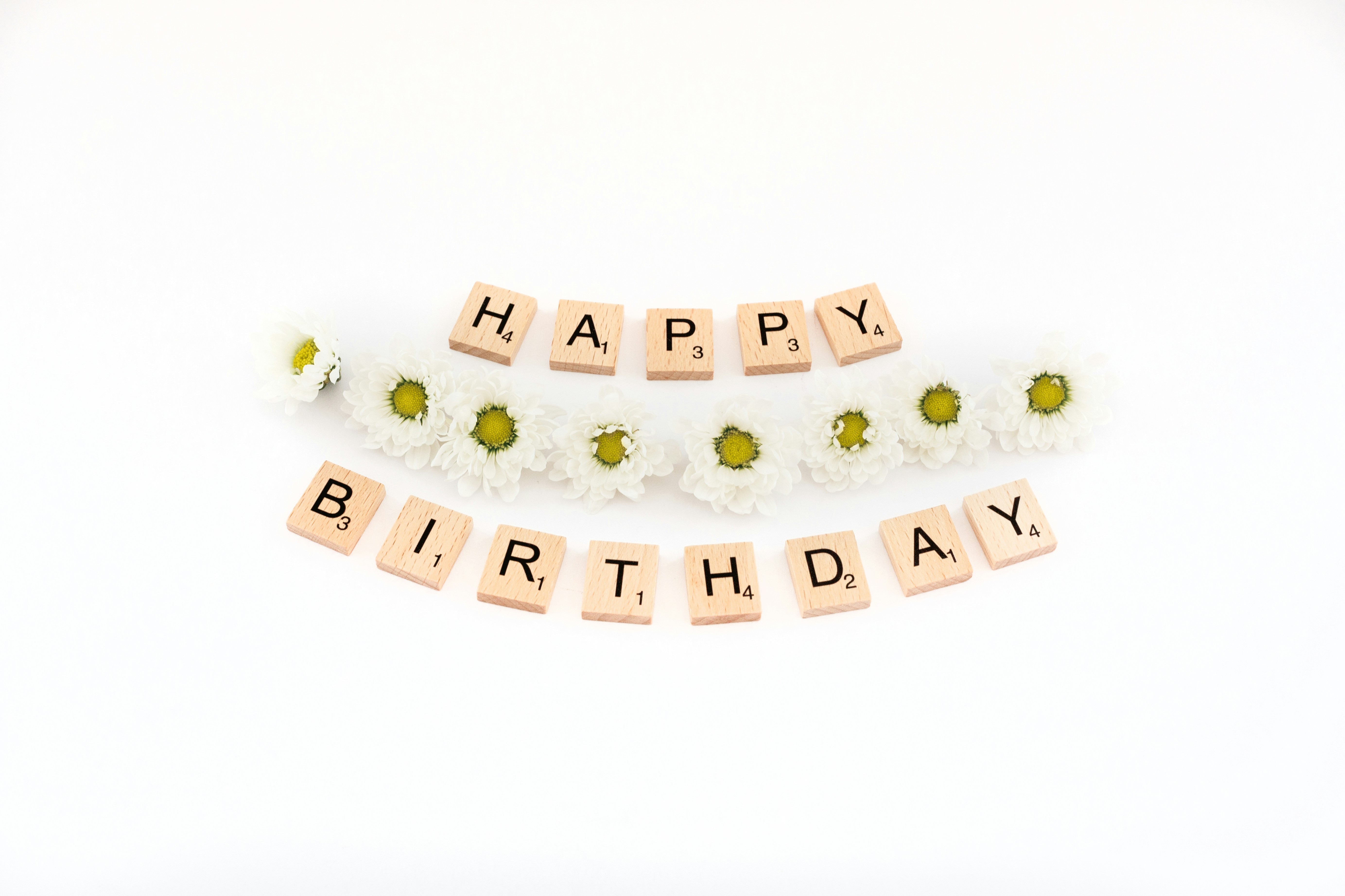 a happy birthday spelled with scrabbles and daisies