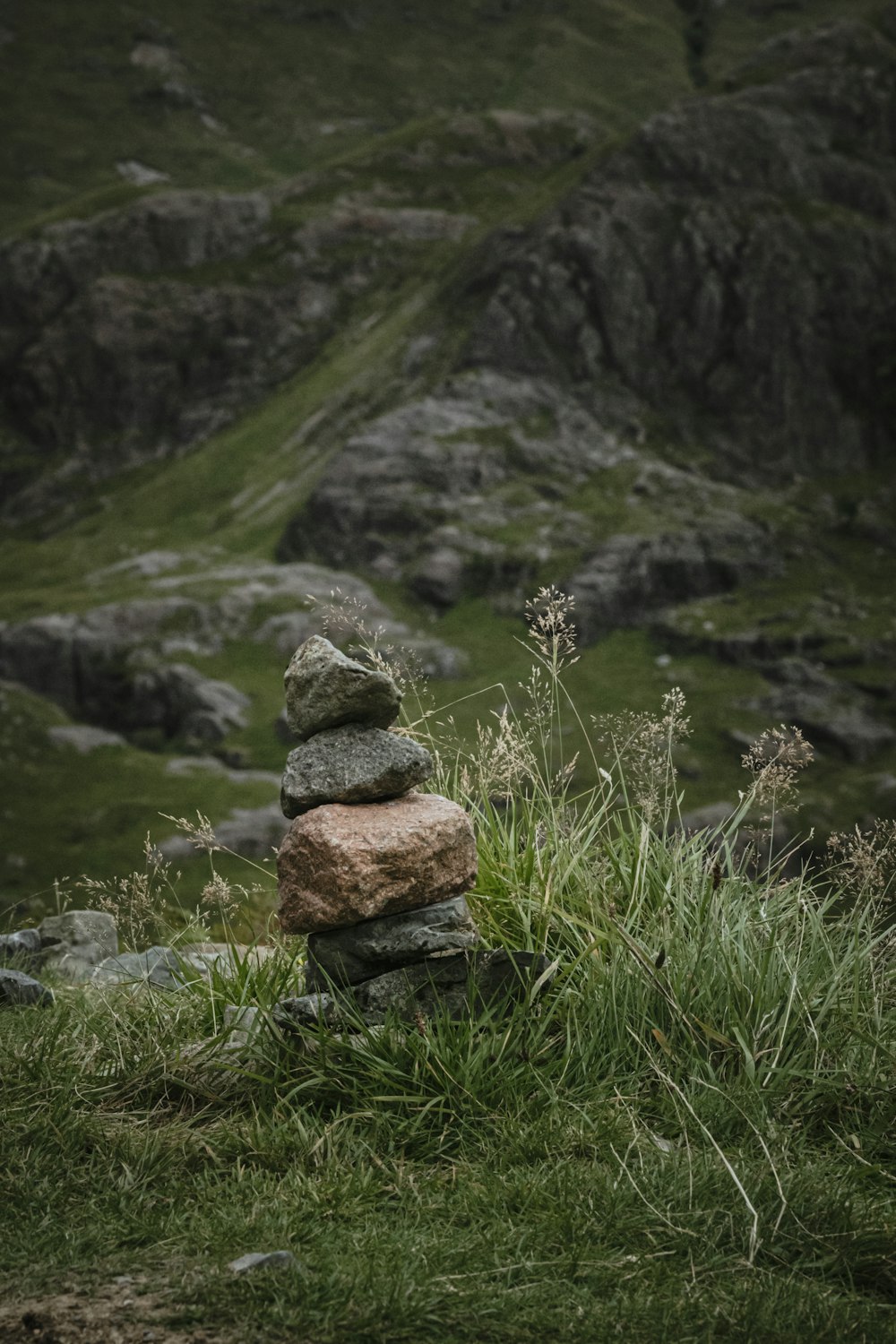 a pile of rocks sitting on top of a lush green hillside