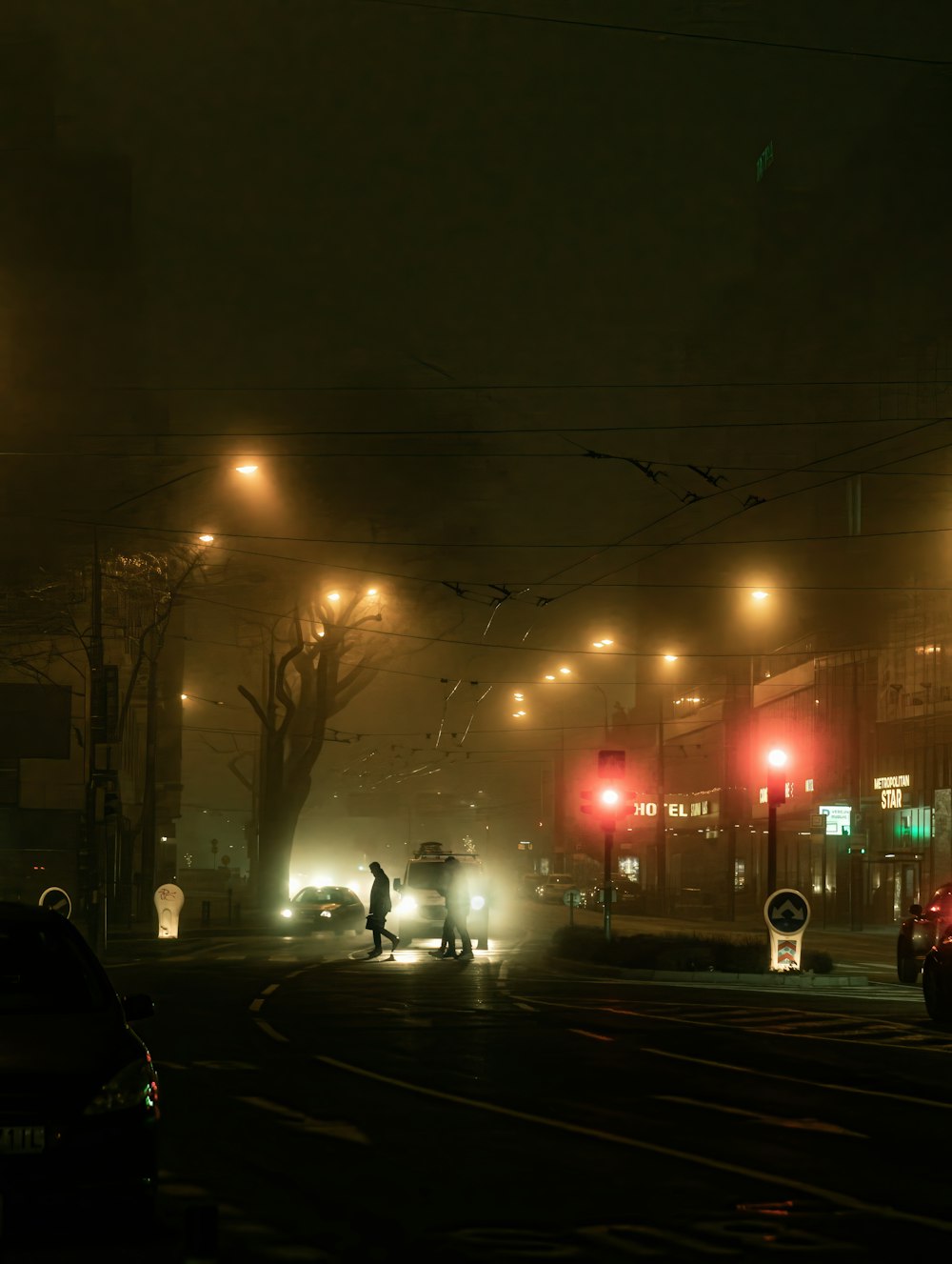 a foggy city street at night with traffic lights
