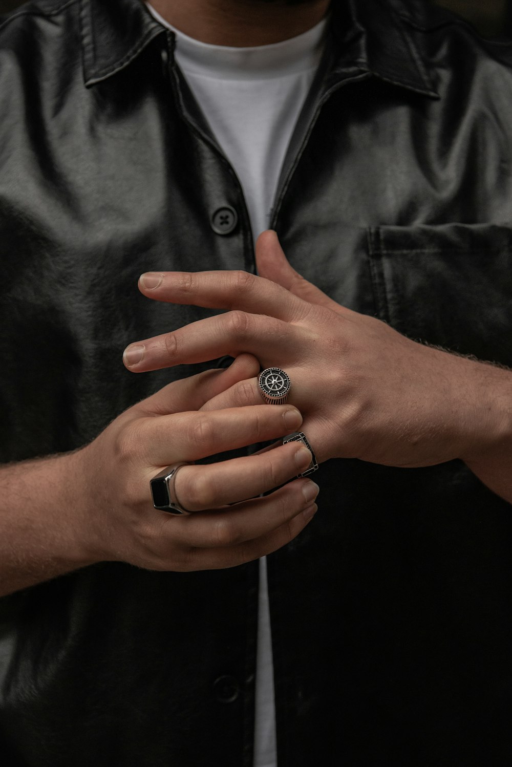 a man wearing a black leather jacket holding his hands together