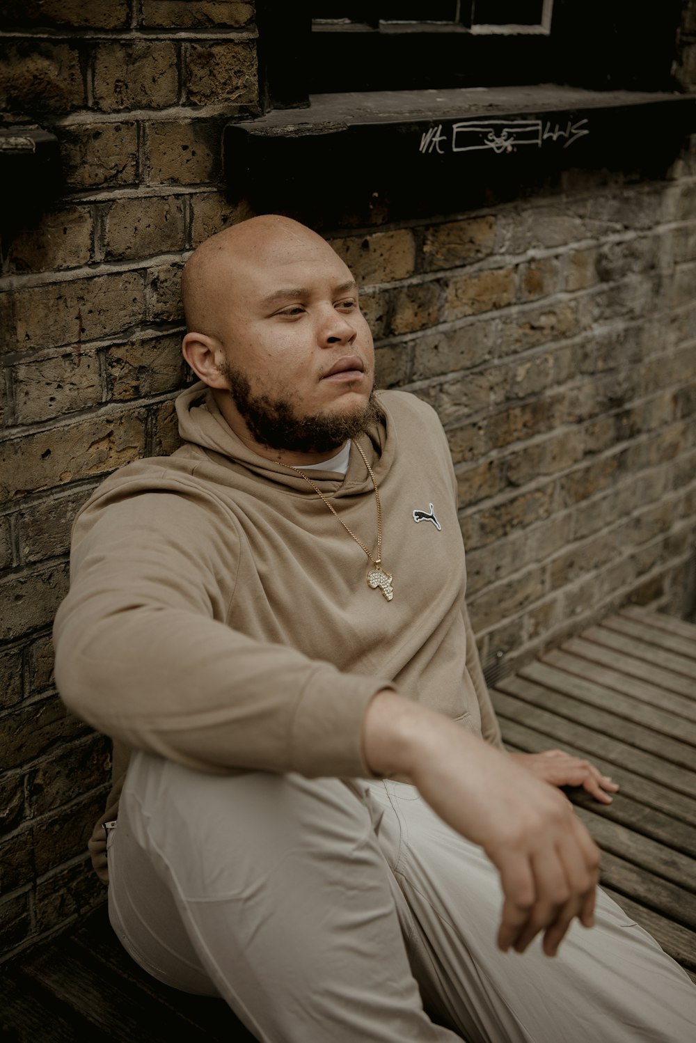 a man sitting against a brick wall