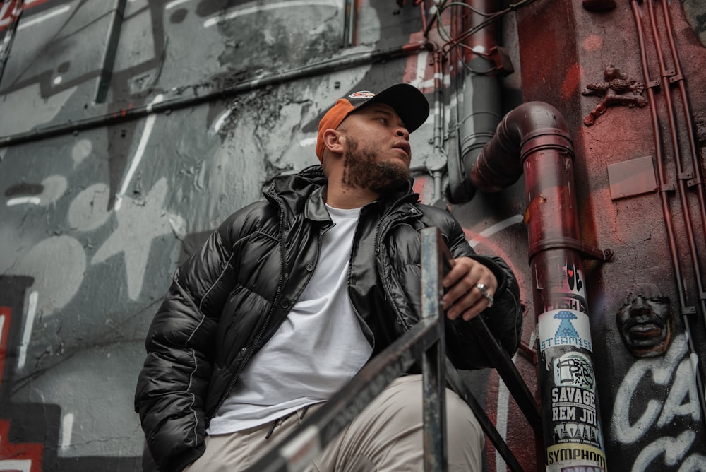 a man leaning against a graffiti covered wall