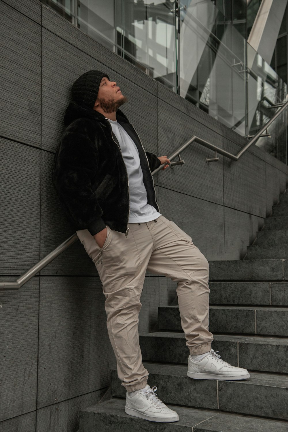 a man leaning against a wall while leaning against a stair rail