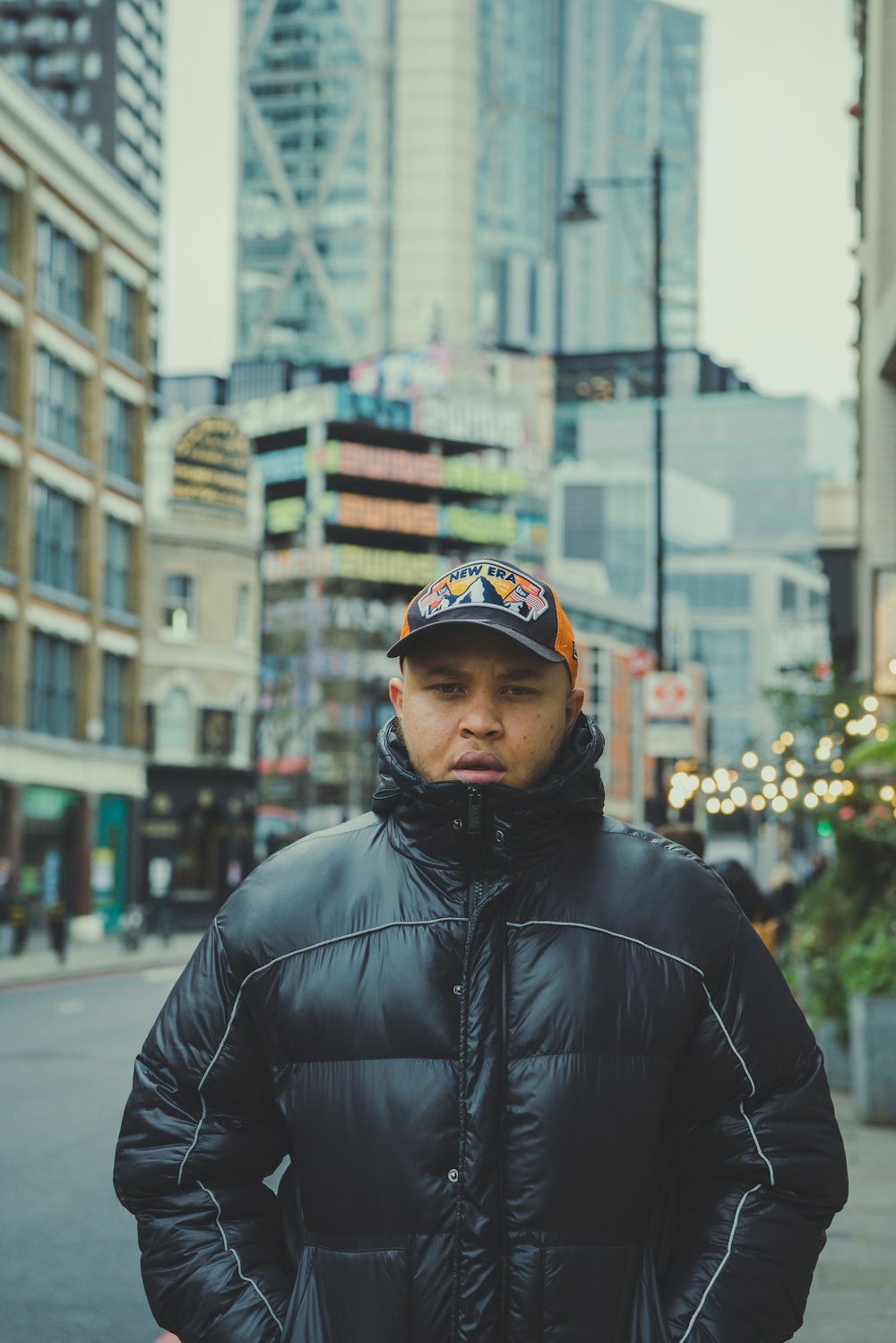 a man standing on a city street wearing a black jacket