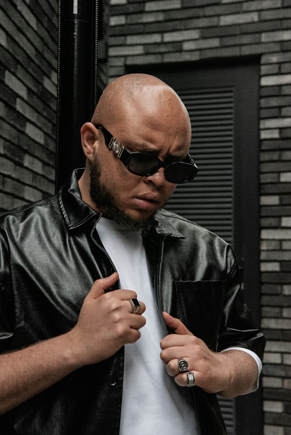 a bald man wearing a black leather jacket and sunglasses
