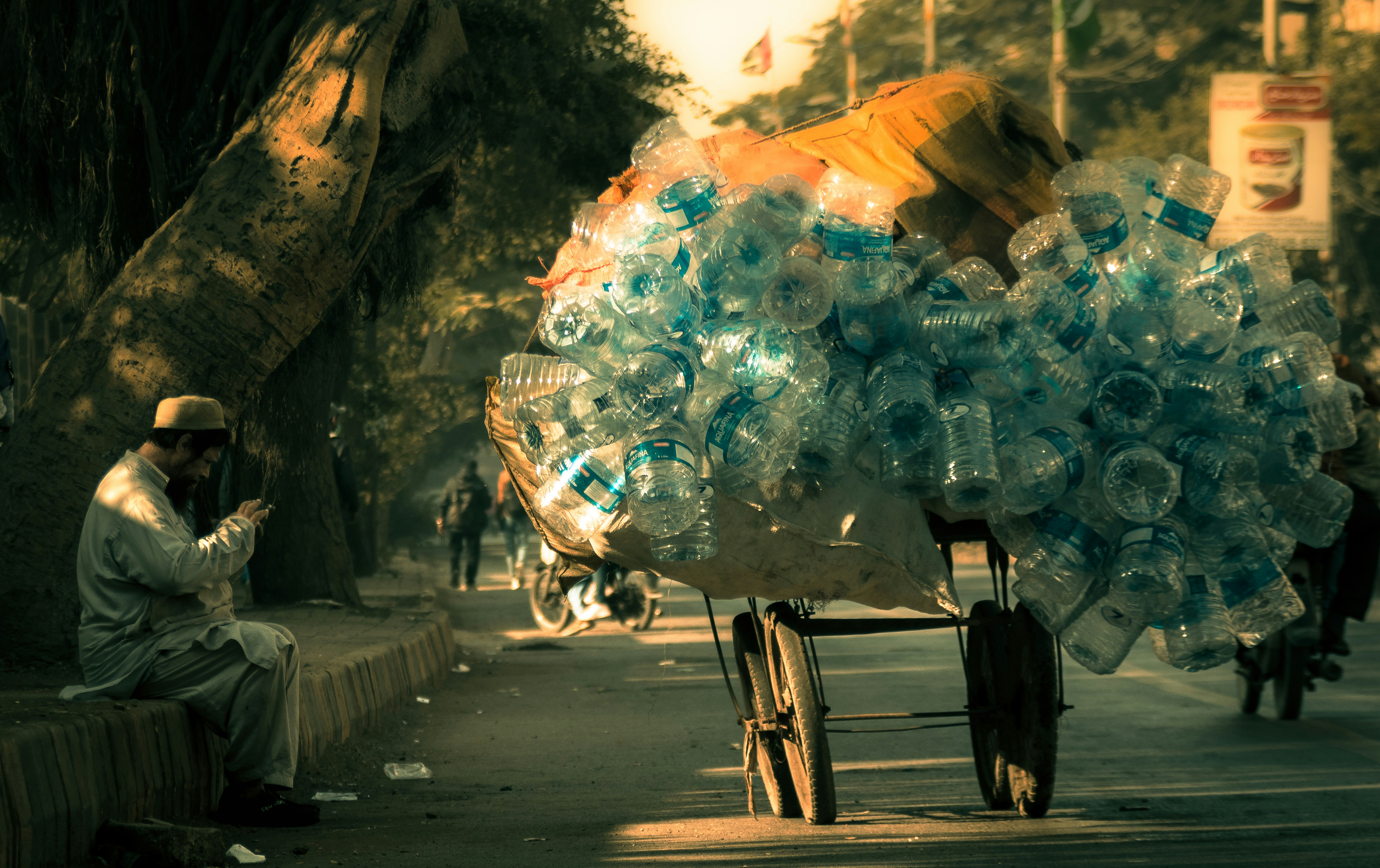 a man sitting on a bench next to a cart full of water bottles