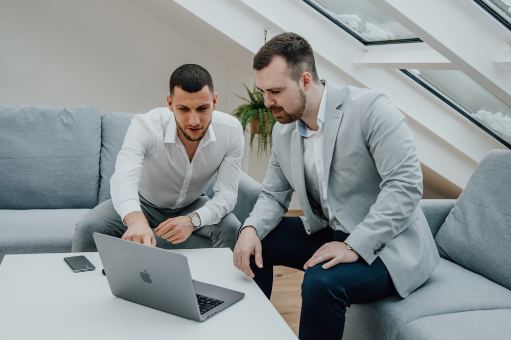 two men looking at a laptop on a table