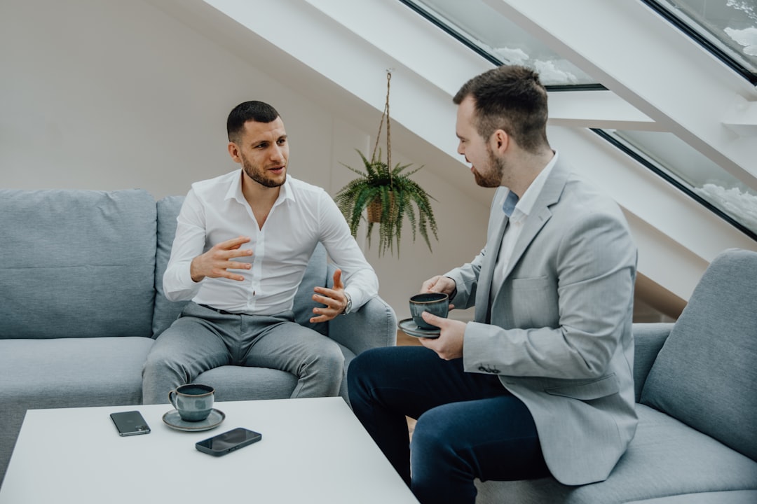 two men sitting on a couch talking to each other,
