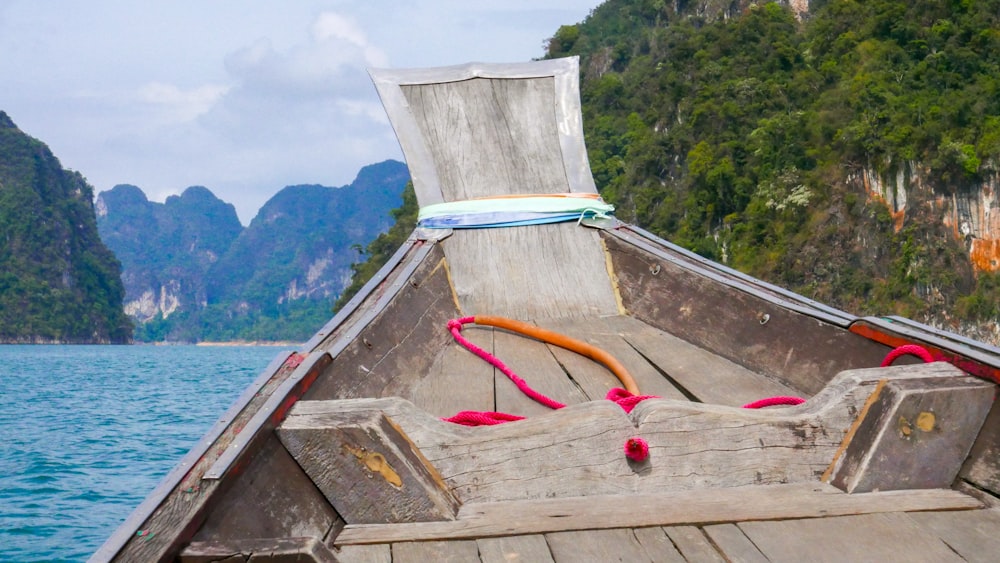 a wooden boat on the water with mountains in the background