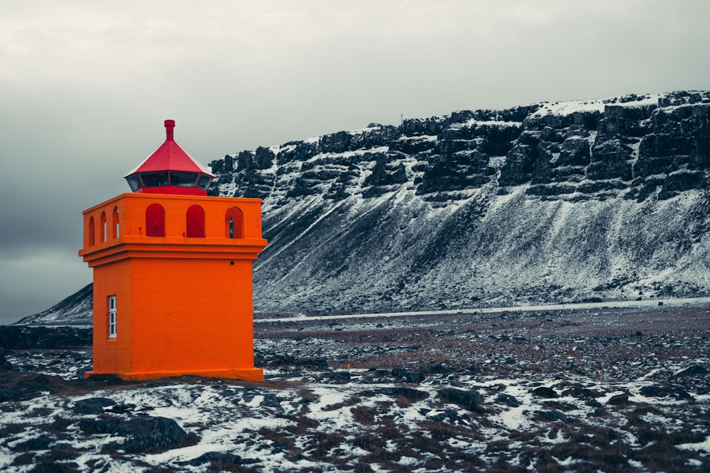 a bright orange lighthouse on a rocky beach