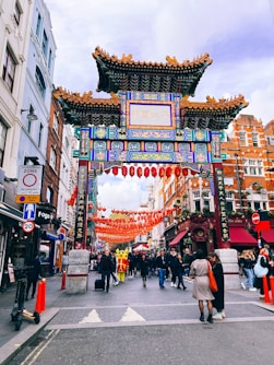 a group of people walking down a street under a colorful archway
