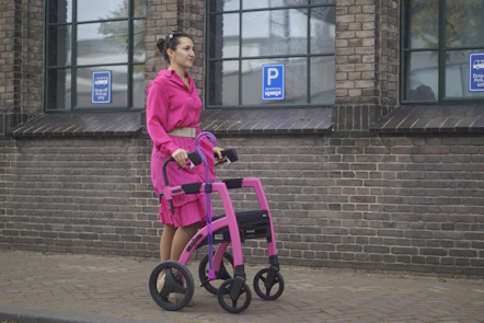 a woman in a pink dress pushing a pink walker