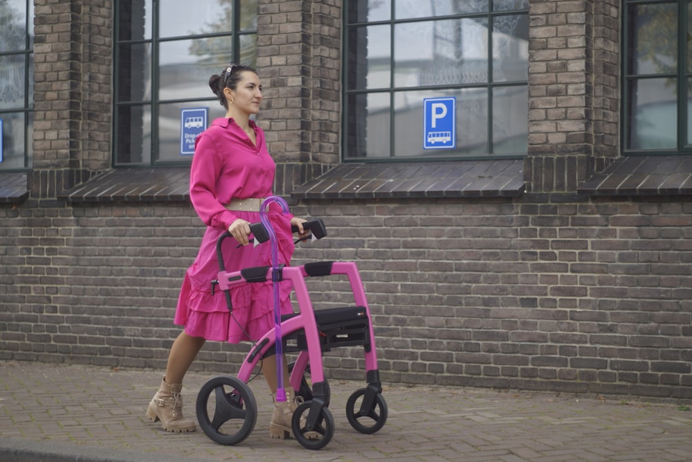 a woman in a pink dress pushing a pink walker