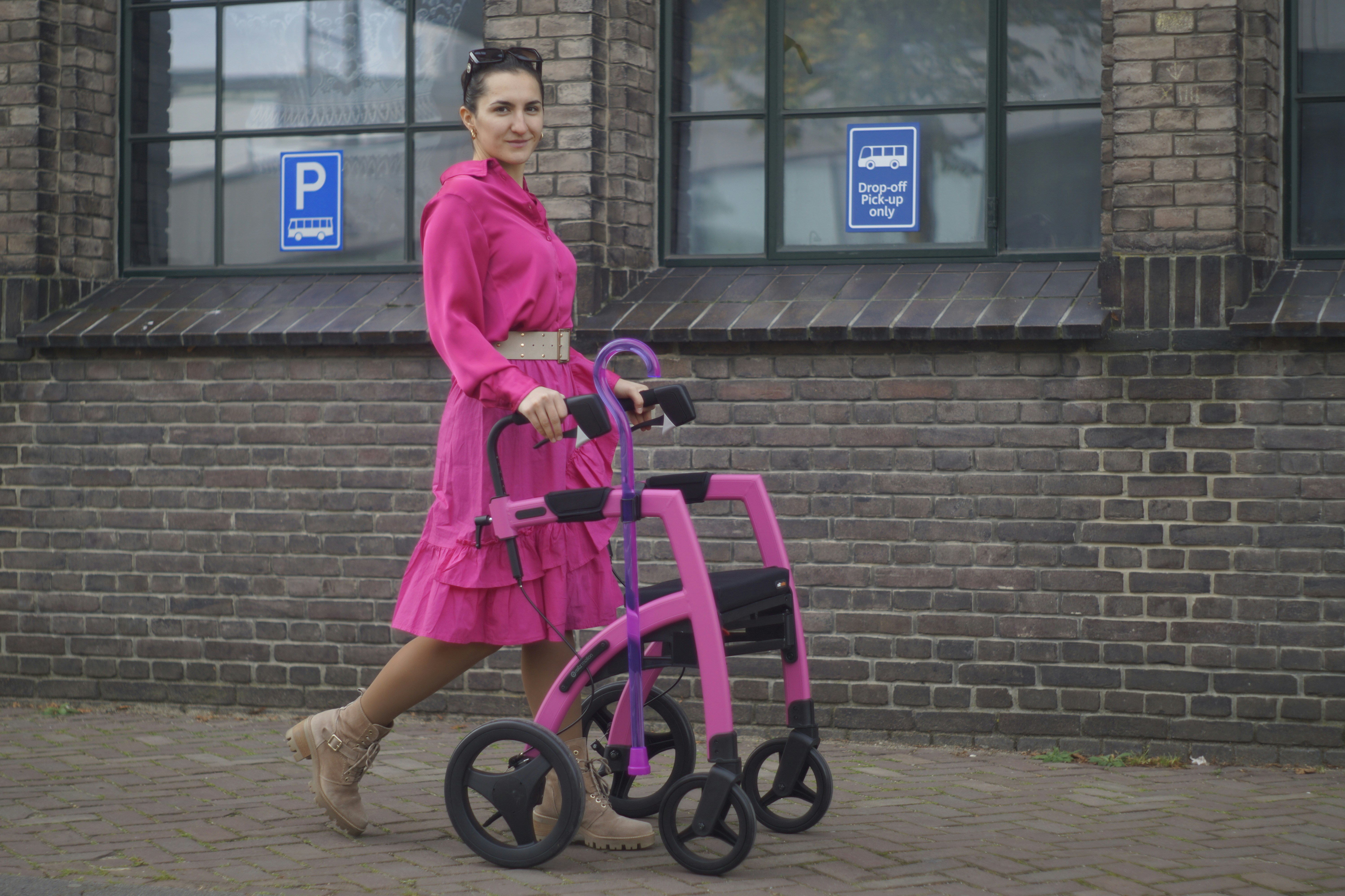 a woman in a pink dress walking with a walker
