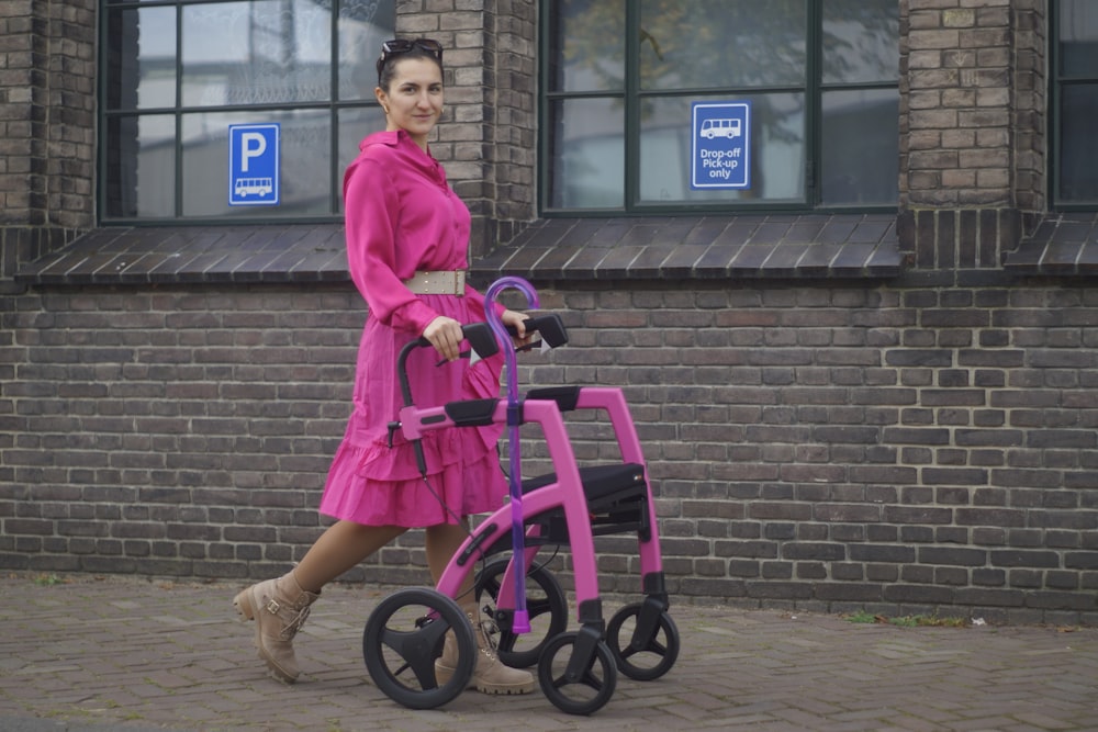 a woman in a pink dress walking with a walker